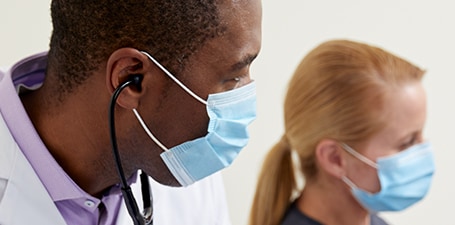 Closeup of a clinician with stethoscope in ears
