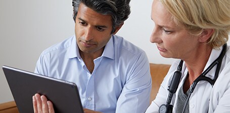 Clinician auscultating and showing man app on a tablet
